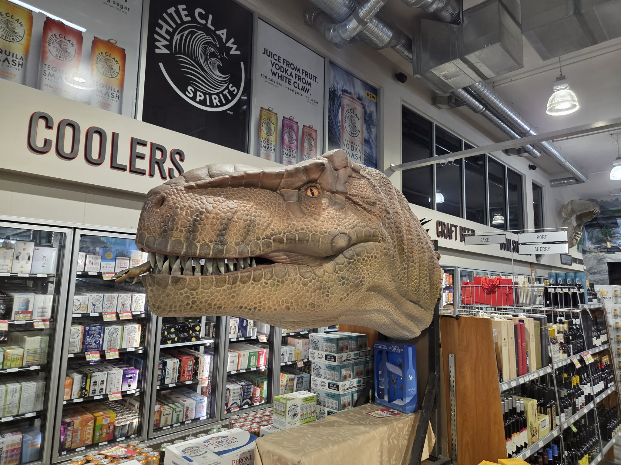 A life-size T-Rex head looming over the Coolers section