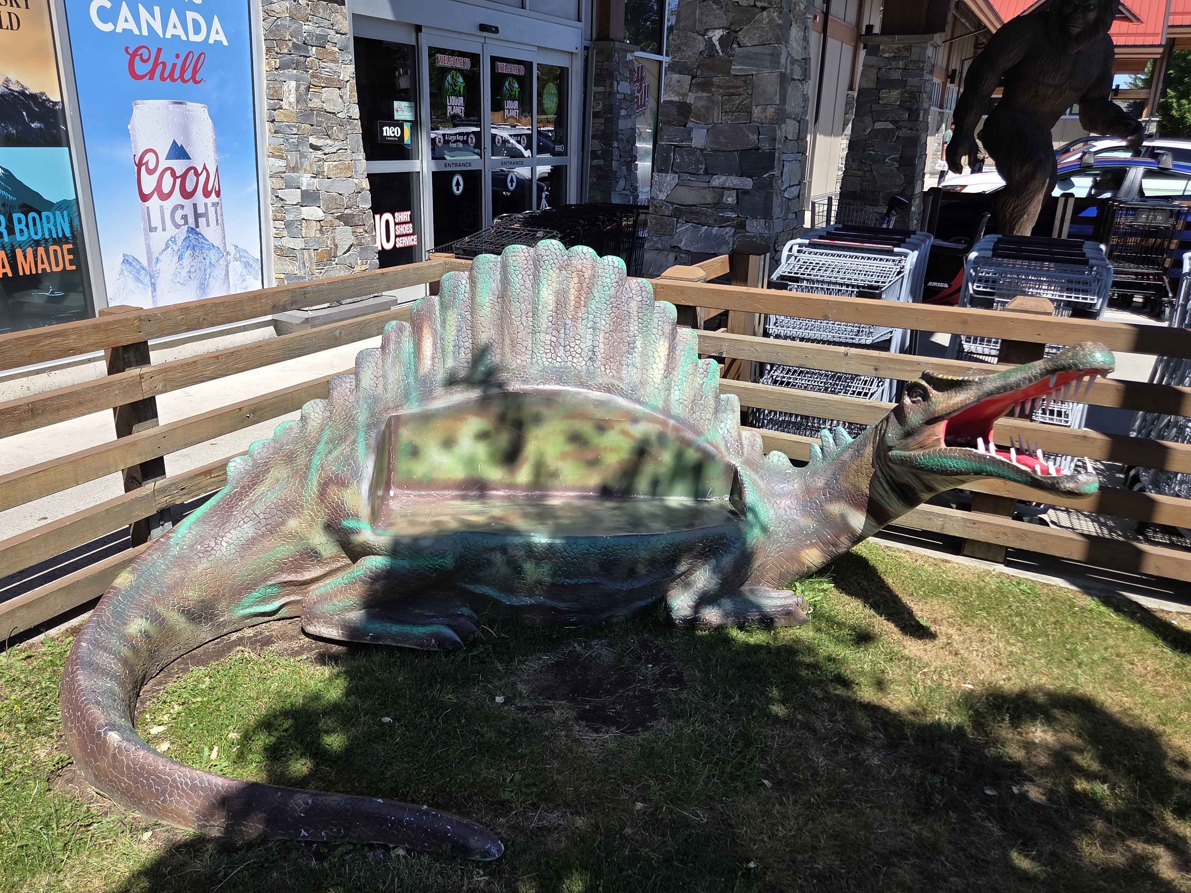 A teal and pink Dimetrodon with its sail-fin back outside near the entrance