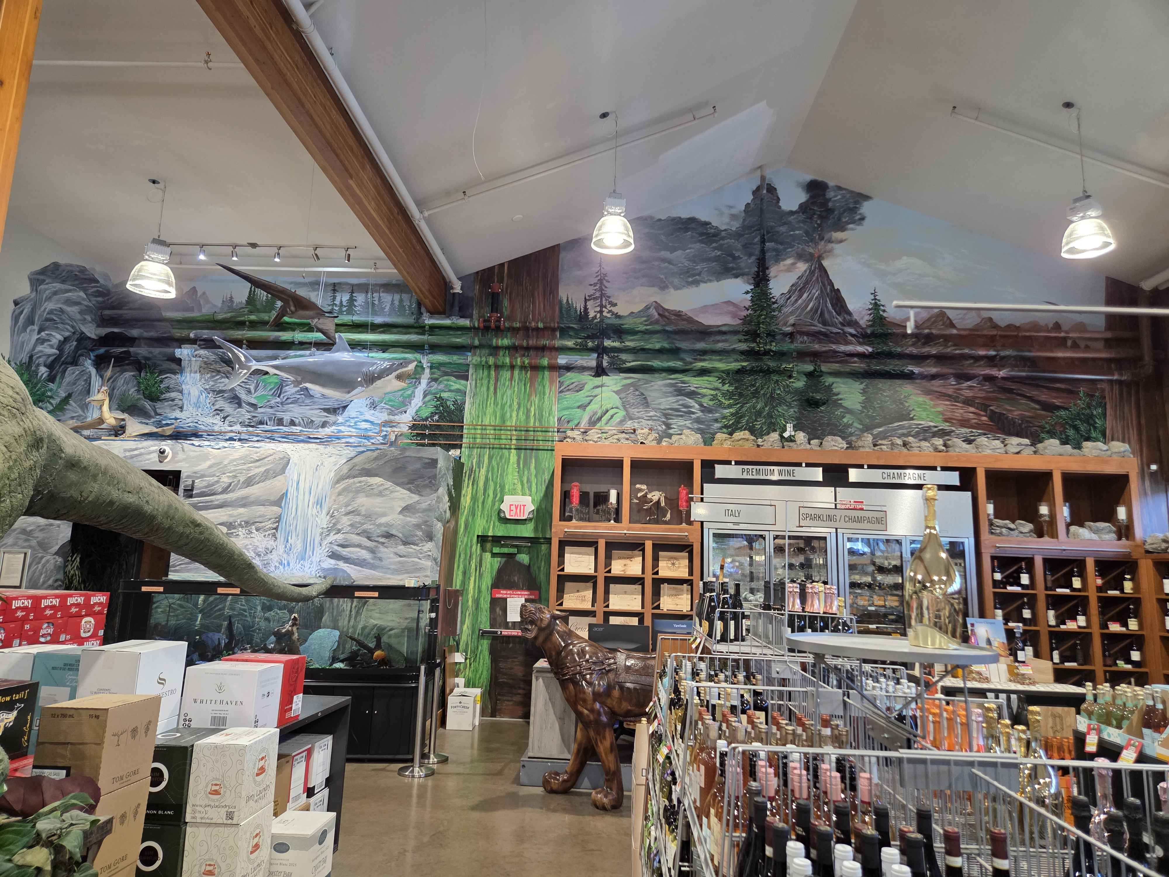 A wide interior shot of the main hall with the painted mural, sauropod tail, volcano, and premium wine section